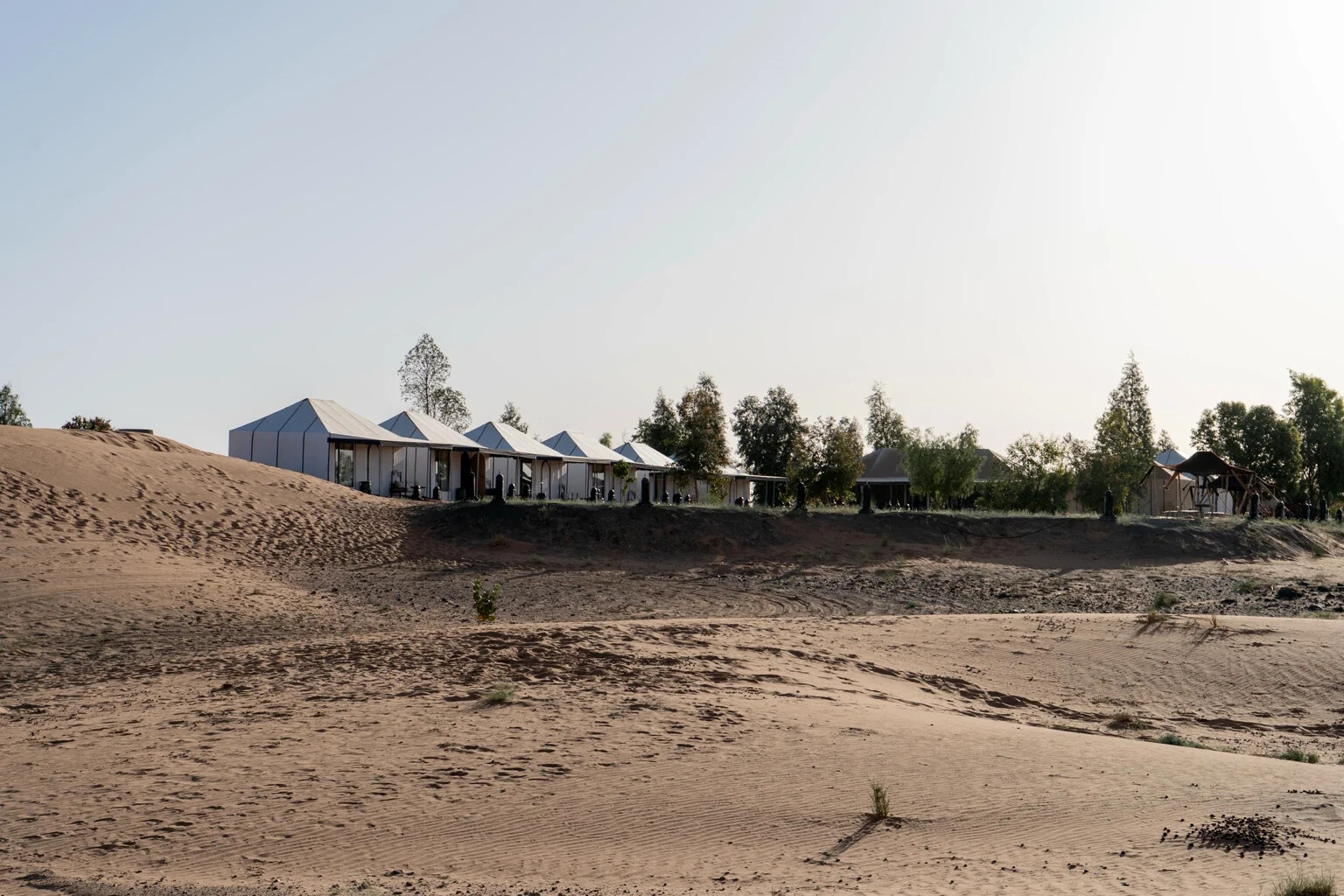 The desert camp seen from the dunes above, tents set at the edge of the Erg Chebbi sand sea